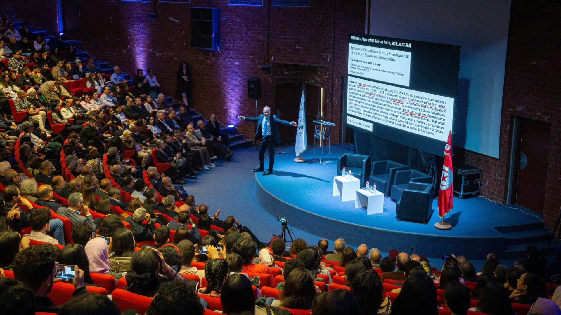 Speaker presenting research to a large conference audience